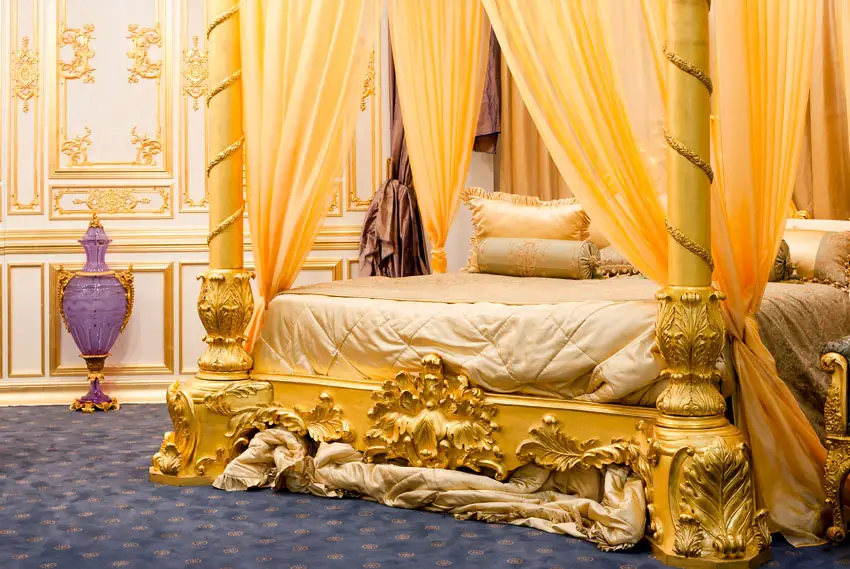 Beautiful four post bed with gold drapery and gilded bed frame