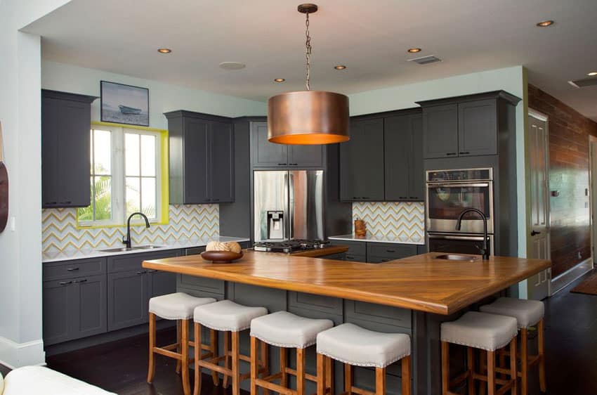 Eclectic kitchen with gray cabinets wood counter colorful backsplash and round pendant light