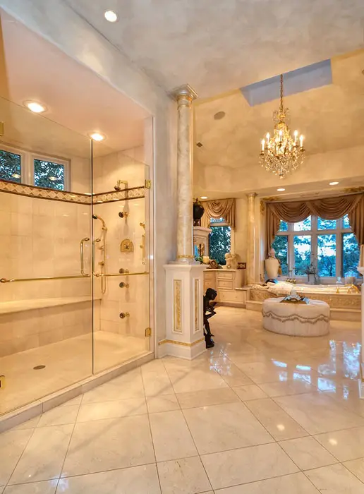 Walls with faux marble finish ornamental columns, crystal chandelier and gold bathroom fixtures