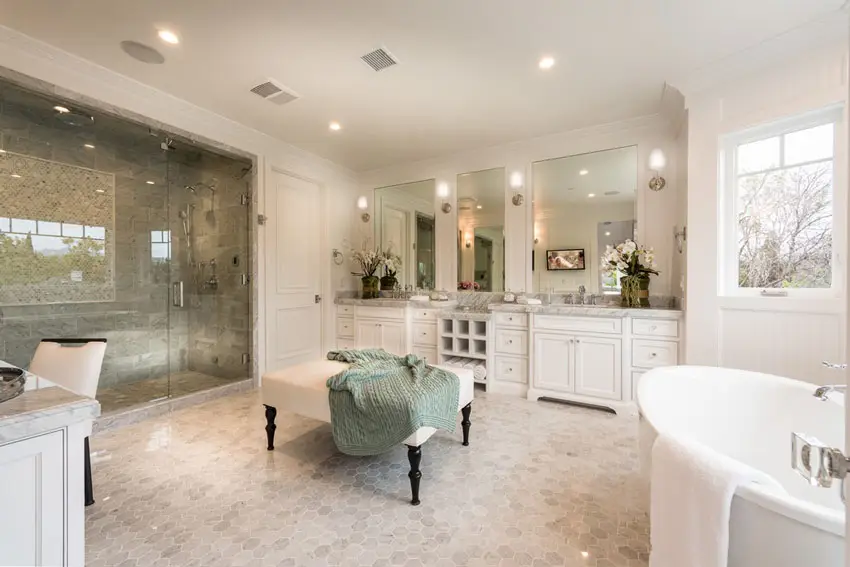 Bathroom with white and gray palette with white paneled cabinets and square ottoman