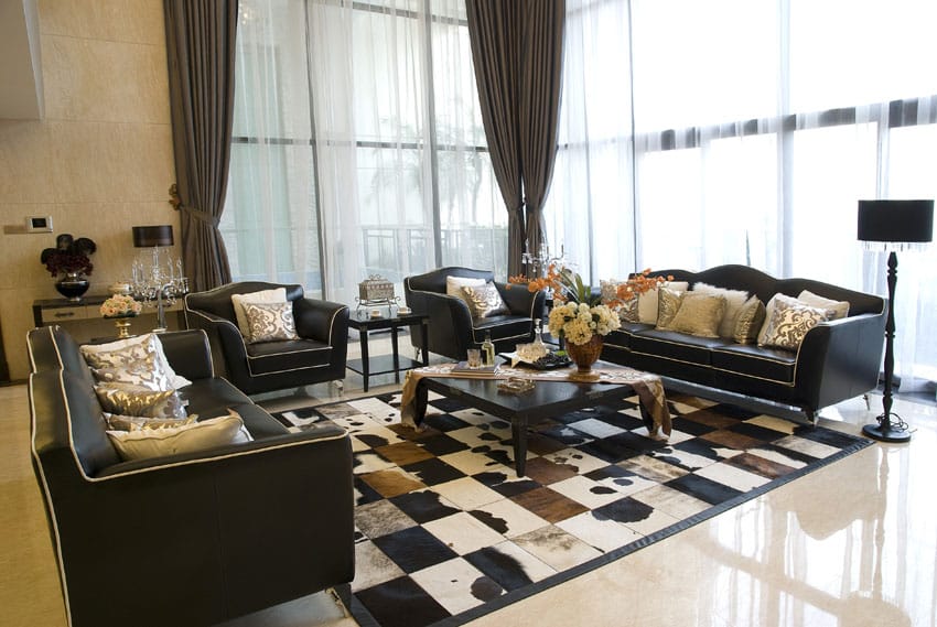 Elegantly furnished drawing room with high windows and dark furniture