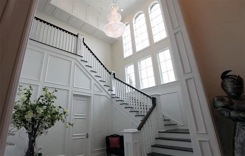 Winding staircase with stained black railing and white balusters