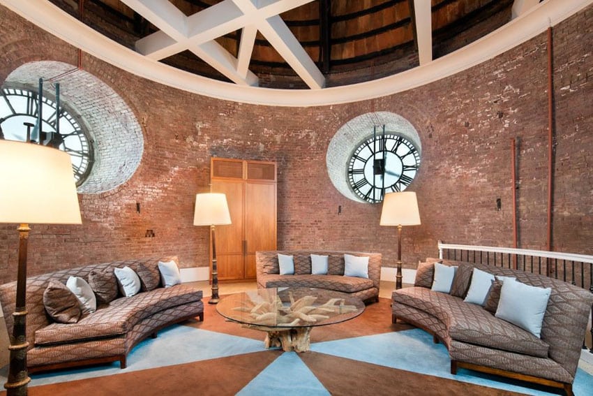 Large circular brick living room with round windows and three curved couches