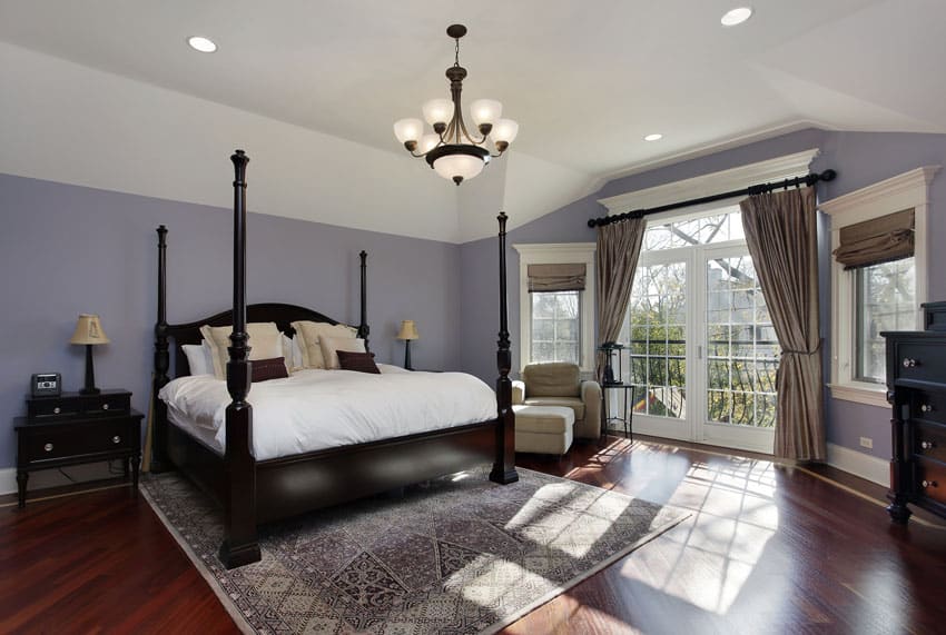 Large bedroom with cherry floors, purple walls and doors to balcony