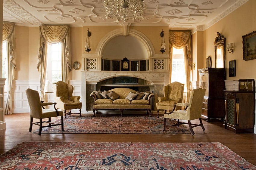 Fireplace with custom mantle, camel back sofa, winged lounge chairs and curtains with drapes