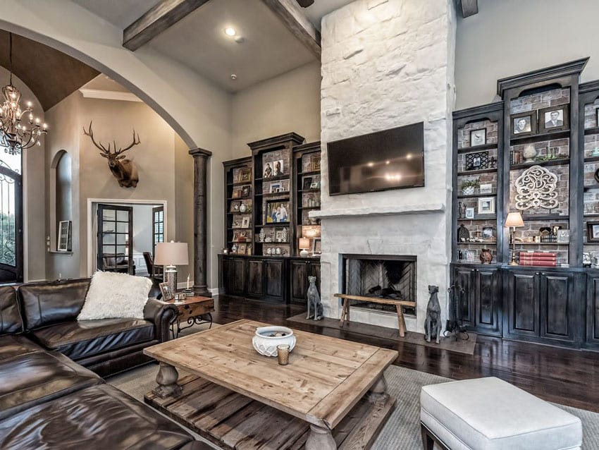 Rustic living room with custom built in bookshelf, chandelier, arched ceiling and fireplace