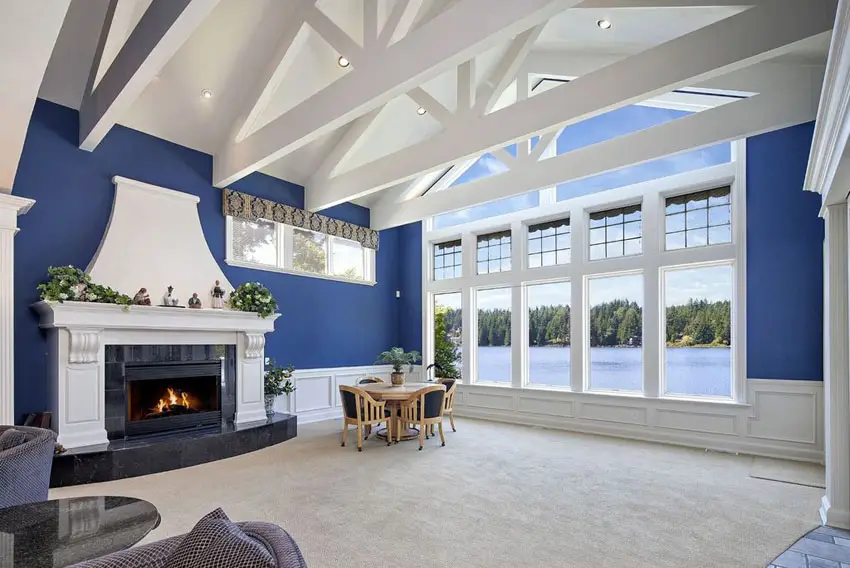 Living room with high vaulted ceilings with painted beams fireplace and lake views