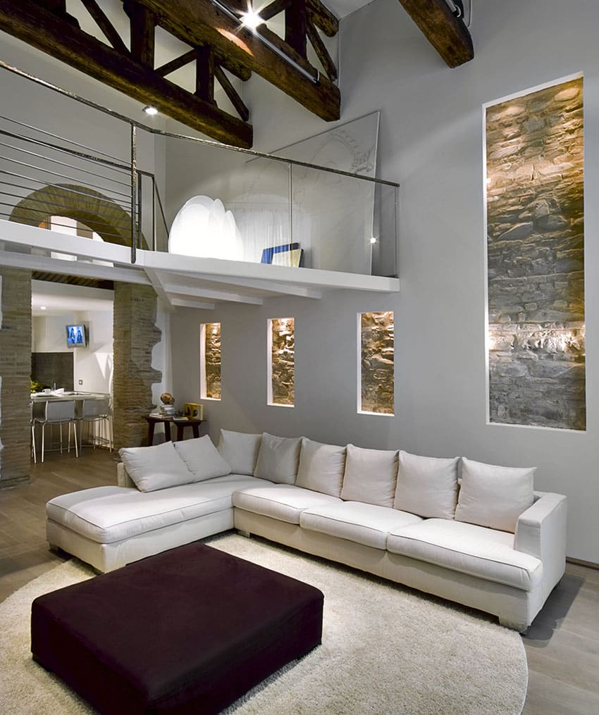 Living room with large white sectional couch high ceiling exposed beams and stone accent wall