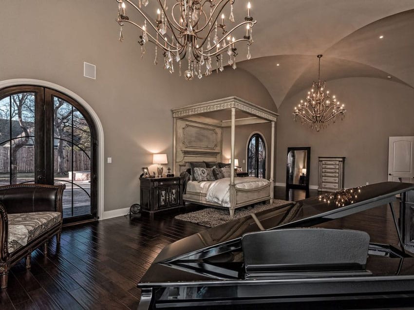 bedroom with four poster bed grand piano and two chandeliers