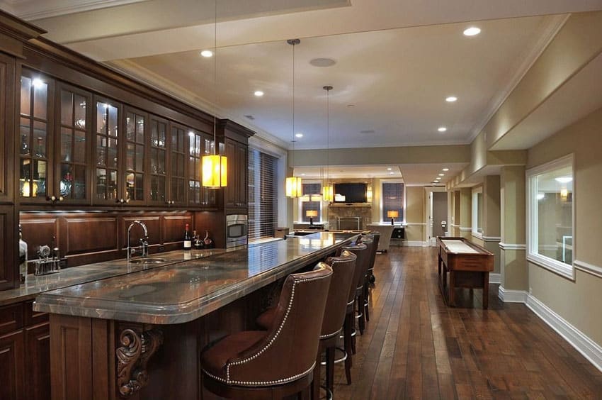 Luxury home bar with dark cabinetry and long granite counter