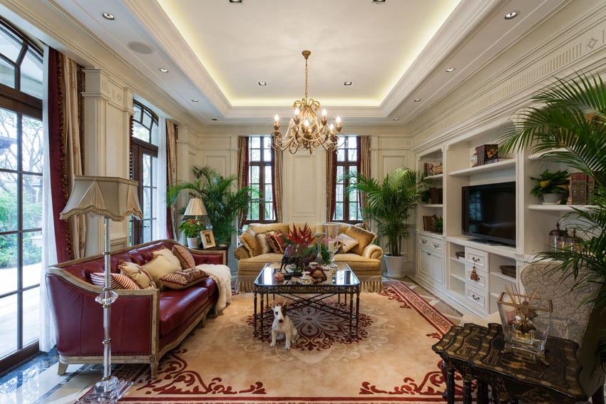 Luxury living room with large windows, polished marble floors, tray ceiling and bronze chandelier