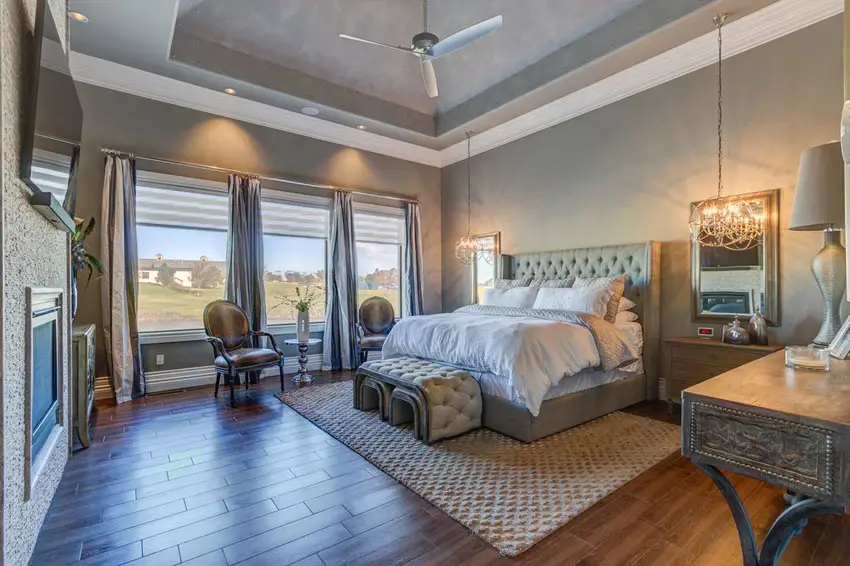 Luxury master bedroom with tufted ottoman and wood floors