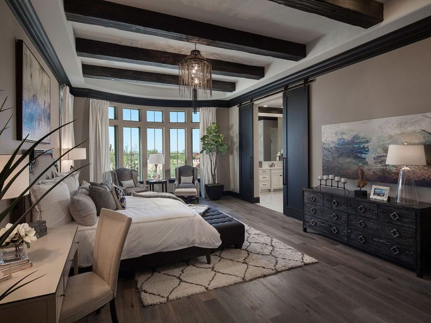 Luxury bedroom with light brown paint, wood flooring and exposed wood beams