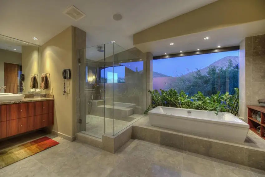 Bathroom with textured tiles, large window and rubber plant placed at the back of the tub