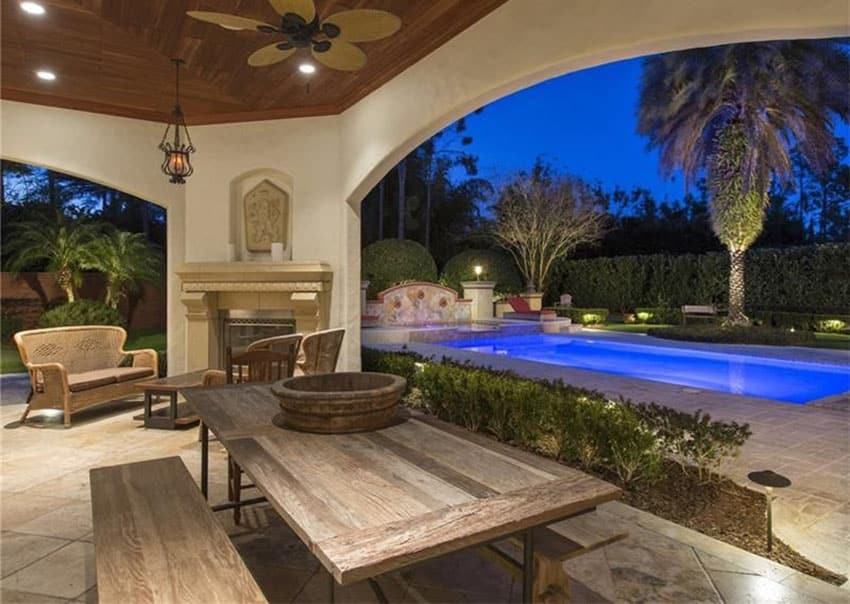 Mediterranean patio with rustic picnic table fireplace and view of pool