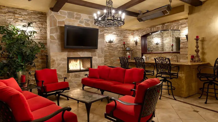 Bar with gas fireplace and natural stone walls and red couches