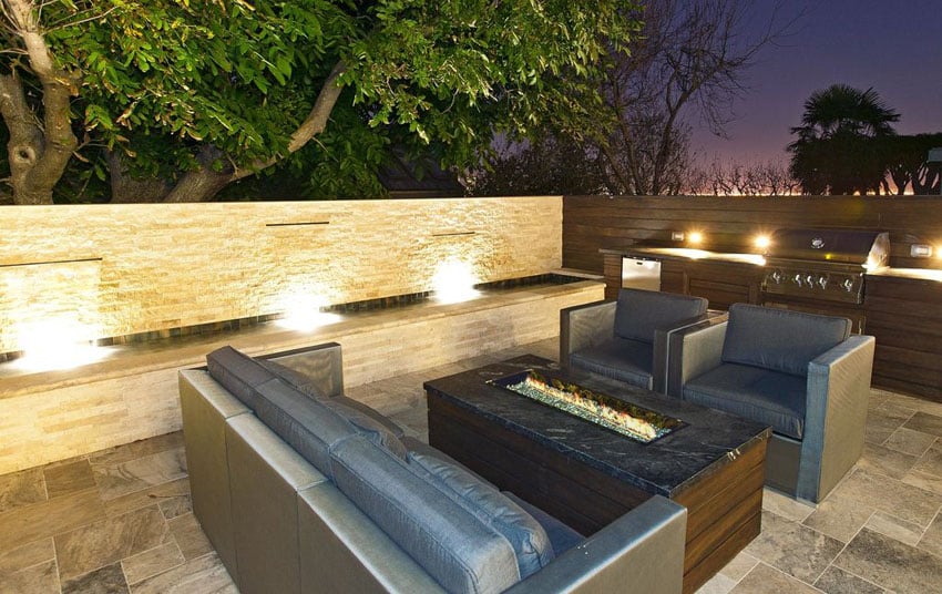 Patio with central firepit and gun metal colored chairs amd water feature