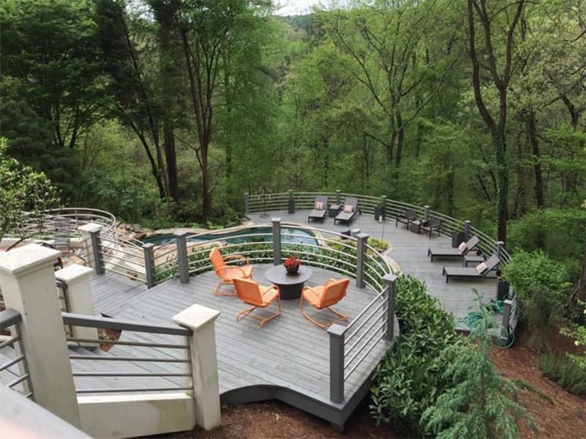 Multiple level deck with metal railings and view of trees from hillside