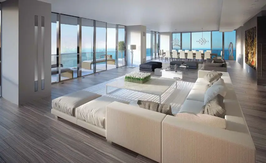 Room with wood grain porcelain floor tiles and white sectional with pillows