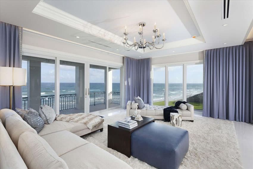 Ocean view living room with white furniture shag area rug purple curtains and chandelier
