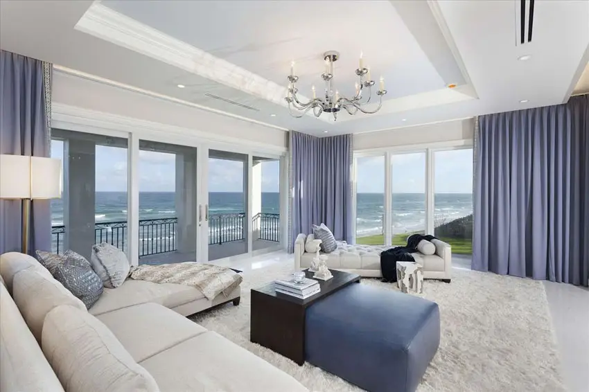 Blue ottoman, shag carpet, white lamp and chandelier