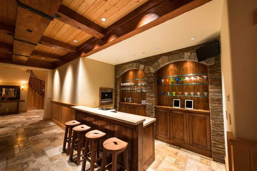 Bar with round stools, open shelves and beadboard ceiling with beams