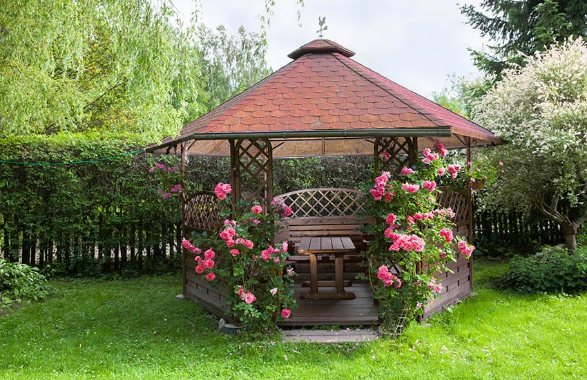 Six sided wood gazebo with bench and shingle roof