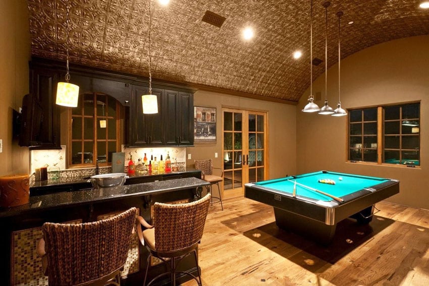 Basement game room with pool table, wicker chairs and steel ceiling