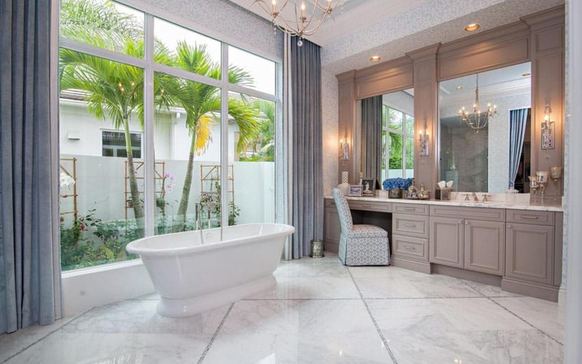 Bathroom with large tiles for the floors, blue floor to ceiling curtains and chandelier