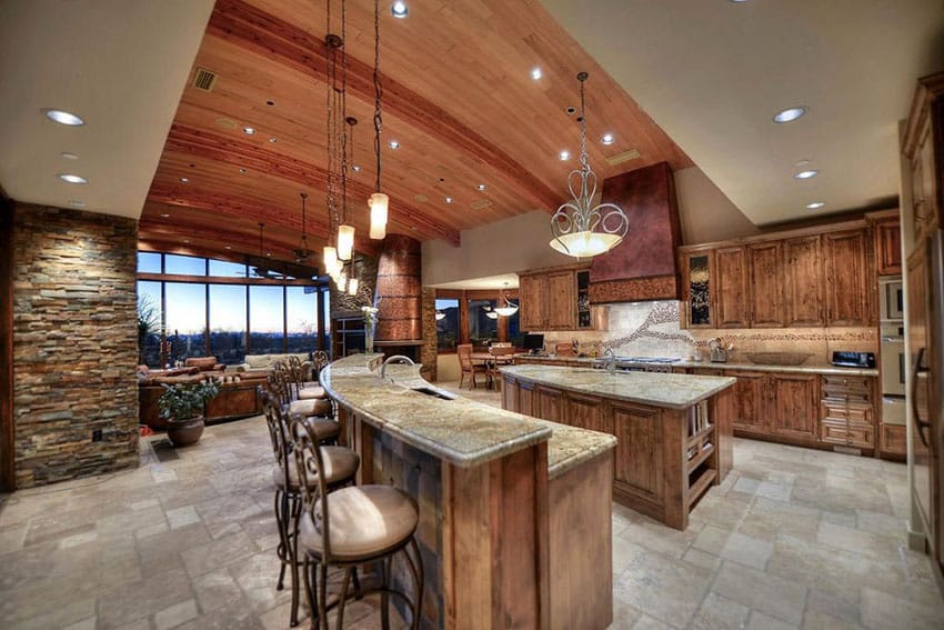 Kitchen with wood plank ceiling, cushion wrought bar stools and natural stone flooring