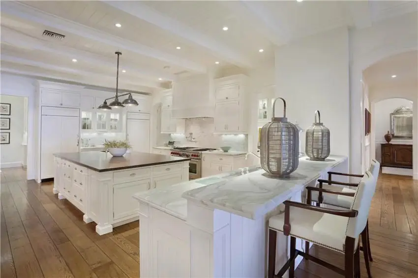 Kitchen with white cabinetry, wood plank flooring and square shaped island