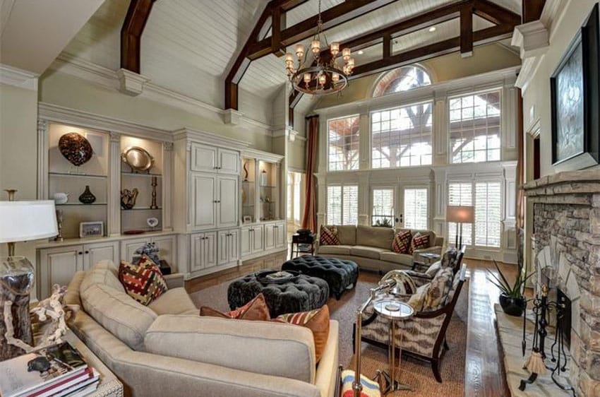 Traditional living room with cream custom cabinets high ceiling and wrought iron chandelier