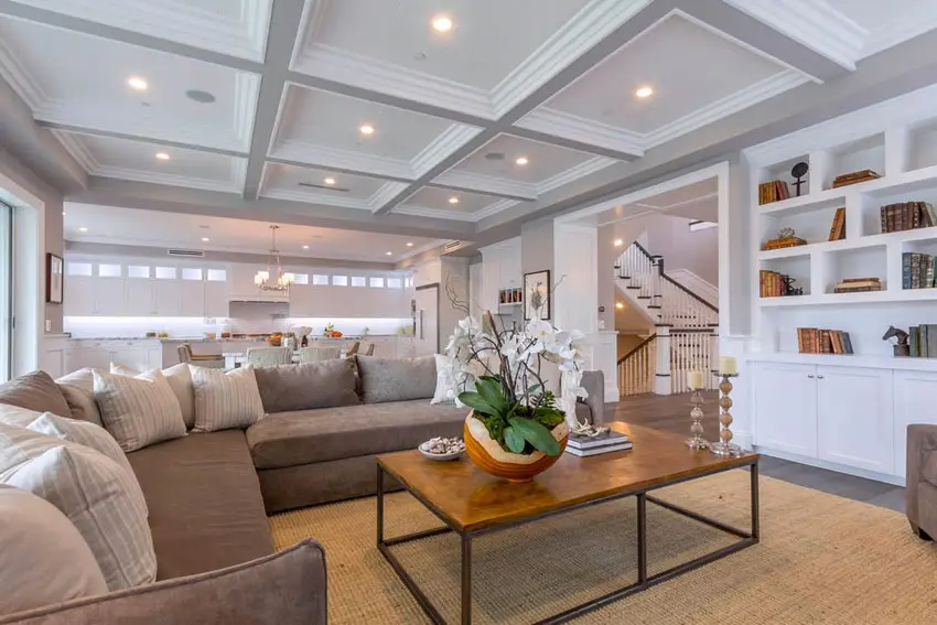 Brown couches, bookshelf, staircase and windows