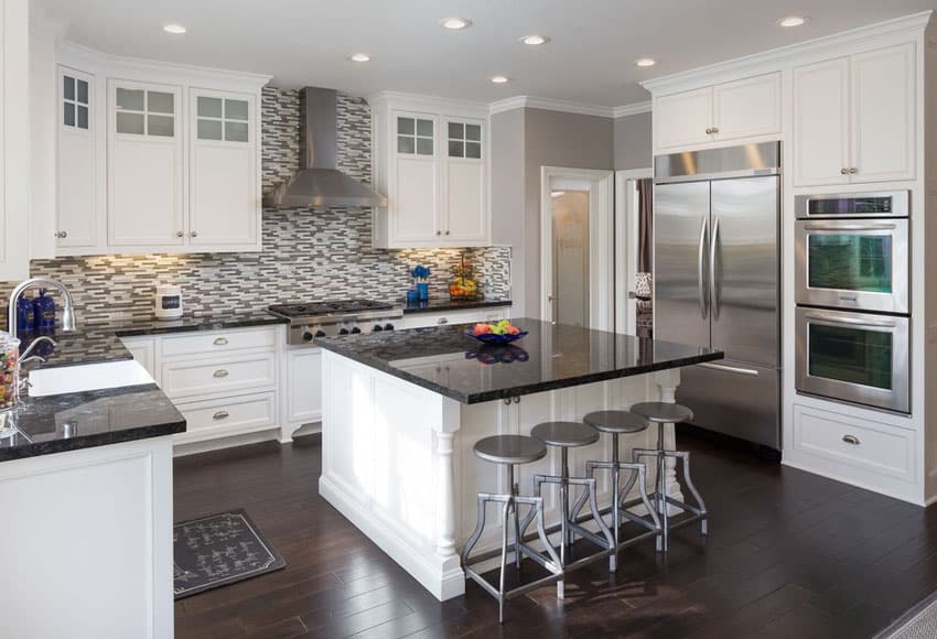 Traditional u shaped white cabinet kitchen with black countertops island and mosaic backsplash
