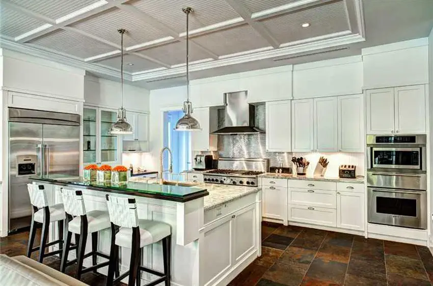 White kitchen with raised glass breakfast bar and slate floor tiles
