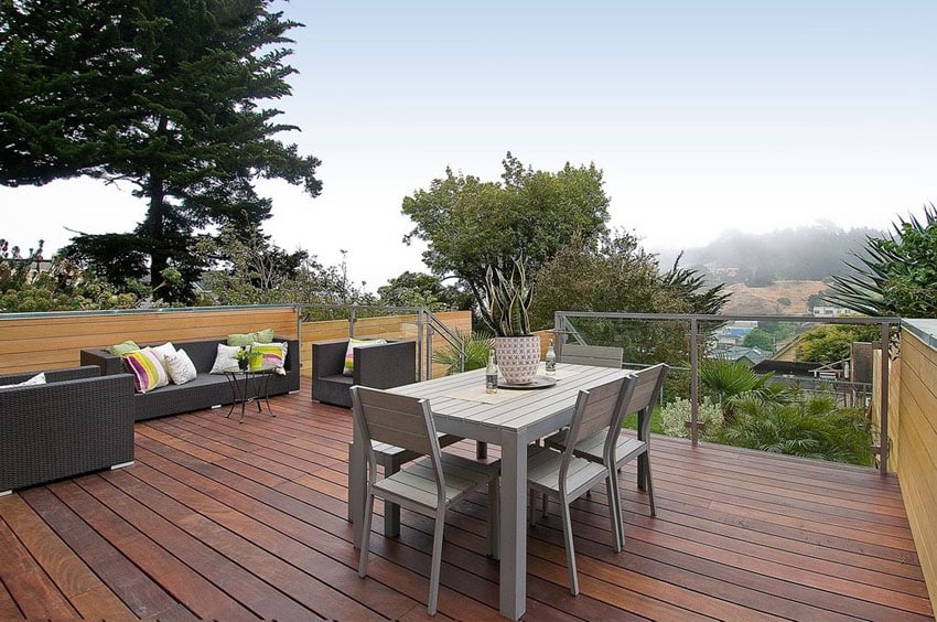 Wood deck with hillside views, synthetic chairs, sofa and outdoor dining table