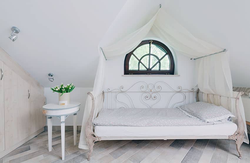 Attic bedroom with white canopy curtain over bed