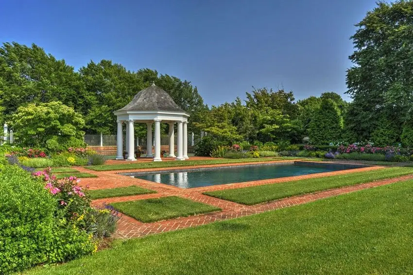 Backyard garden pool next to brick path and pillar gazebo