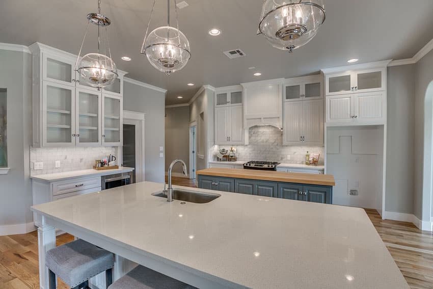 Beautiful kitchen with sparkling white quartz counter island, butcher block island and marble backsplash