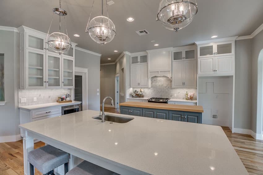 Kitchen with glass cabinets, globe type lights and gray base cabinets