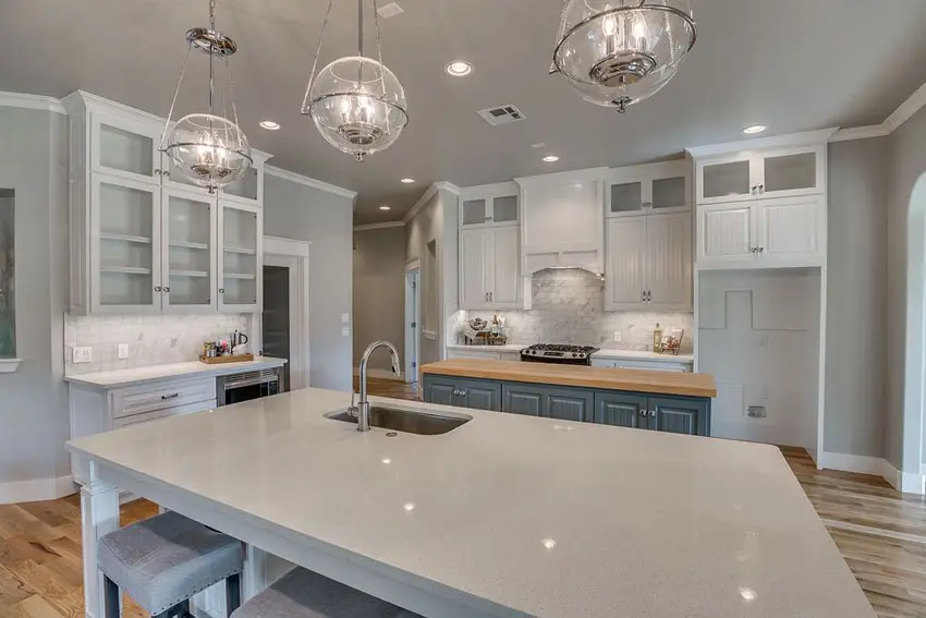 Beautiful kitchen with sparkling white quartz counter island butcher block island and marble backsplash