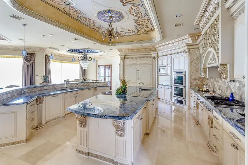 Beautiful Mediterranean kitchen with decorative molded cabinetry, jewel tone granite counters and chandelier