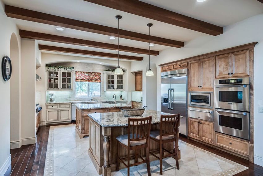 Beautiful traditional kitchen with two islands, decorative woodwork, exposed beam ceiling and wood plank floors
