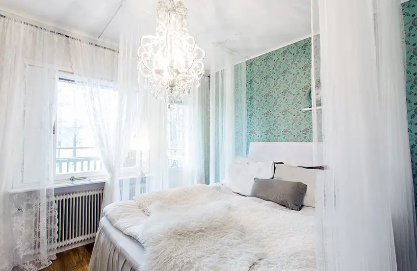 Bedroom with vintage patterned wallpaper and white sheer curtains