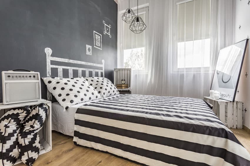 Black and white decor bedroom with chalkboard wall and hanging Edison lamps