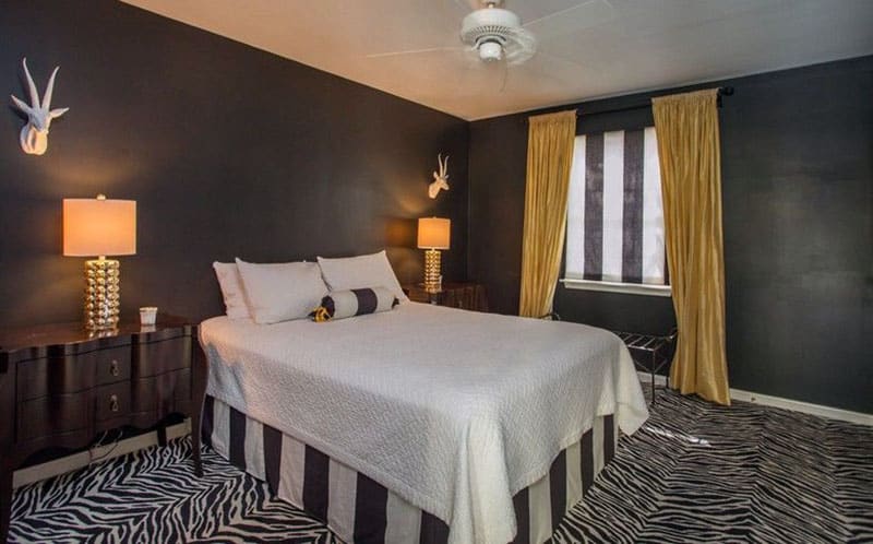 Black bedroom with gold curtains, zebra pattern carpet and black and white decor