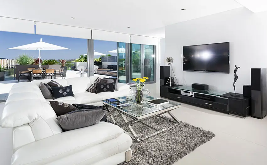 Clean white living room with black entertainment center and large sliding doors to outdoor rooftop patio