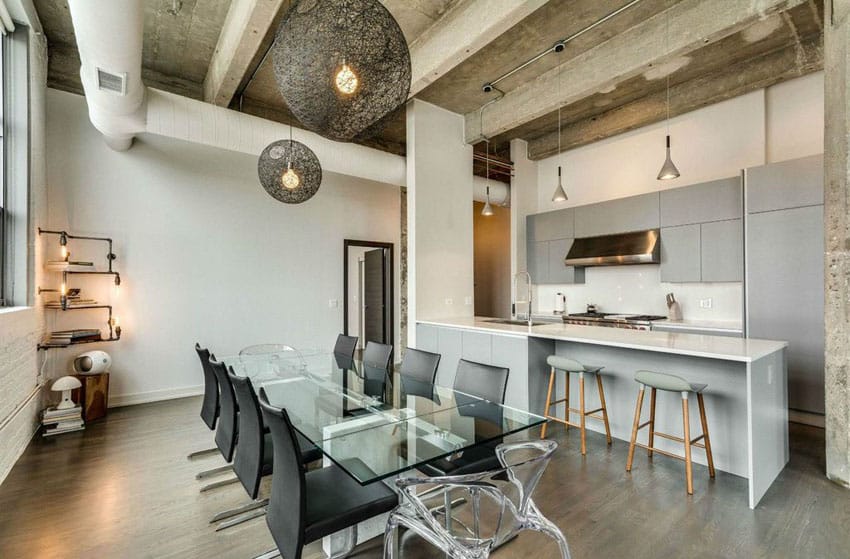 Contemporary kitchen with industrial design gray cabinets and white counter peninsula with glass dining table