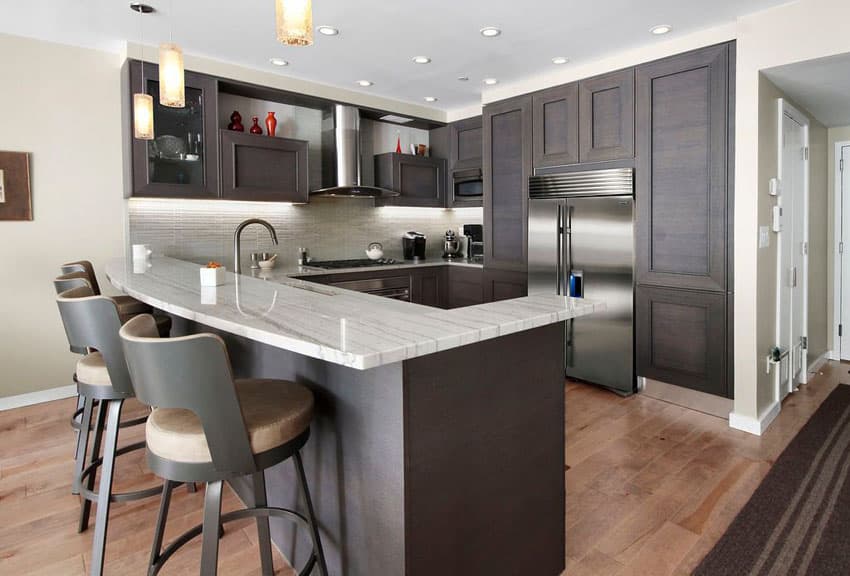 kitchen with overhang peninsula, dark stain cabinets and mini pendants