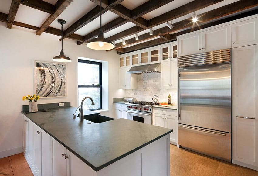 Contemporary kitchen with peninsula soapstone counters exposed beams and white shaker cabinets